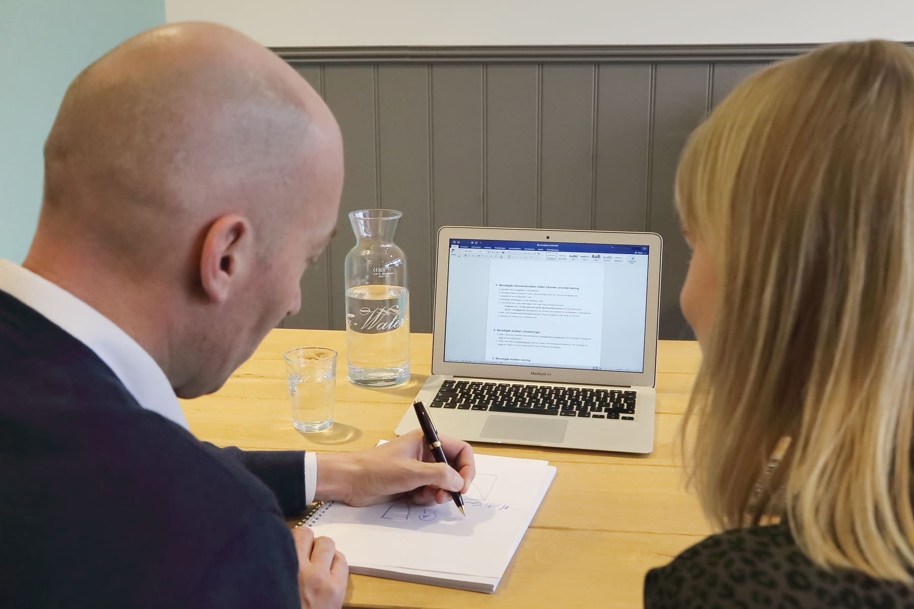Adviseur maakt aantekeningen tijdens een gesprek met een klant