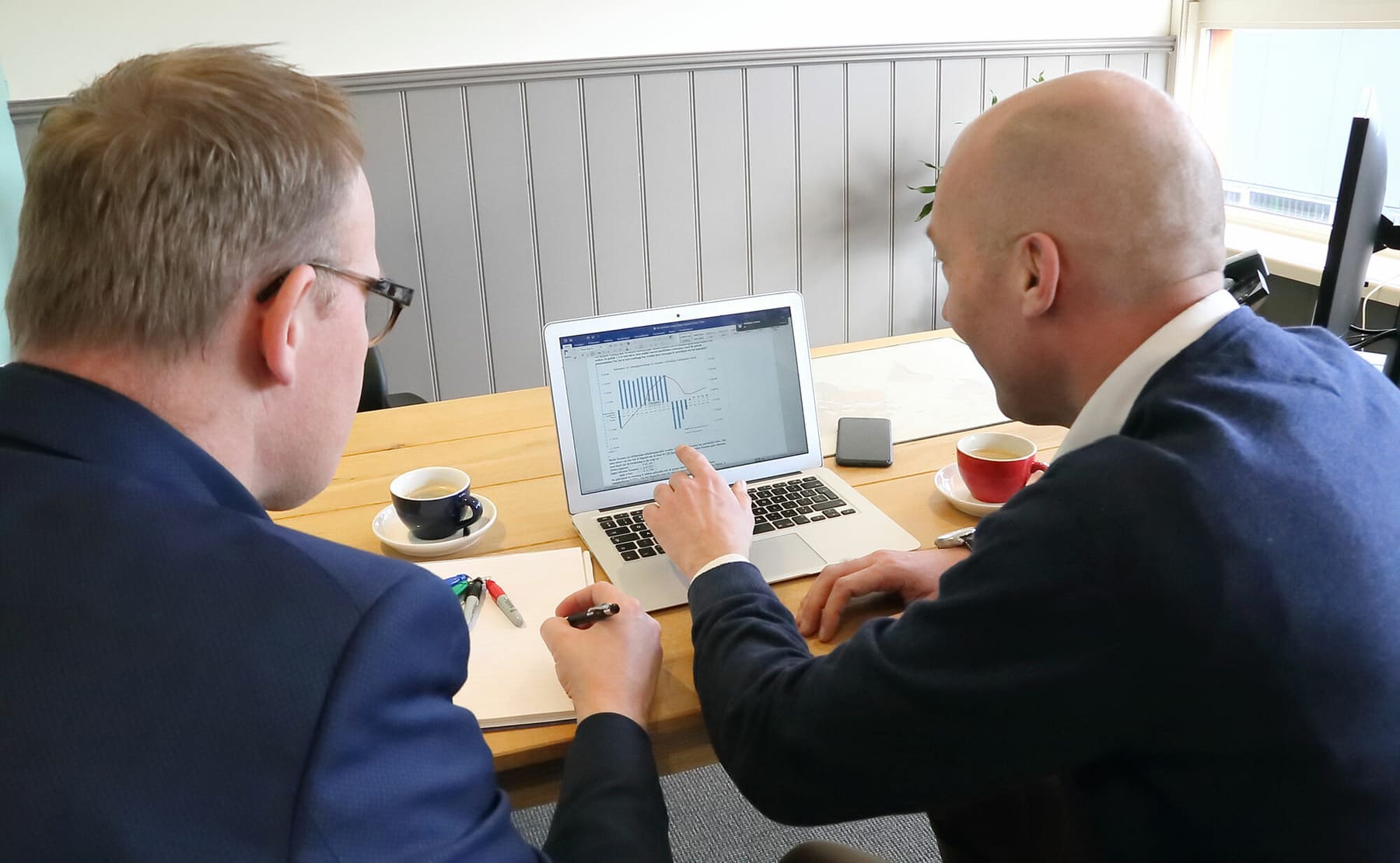 Adviseur en klant bekijken samen een grafiek op een laptop